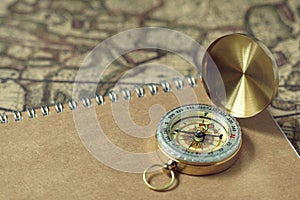 Compass and notebook on blur vintage world map, journey concept, copy space