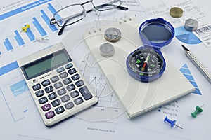 Compass, pen and coin on notebook, accounting background