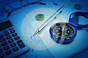 Compass, pen, glasses and coin on notebook, business vision concept