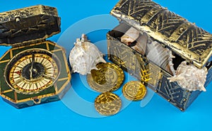 Compass and pirate coins on blue background