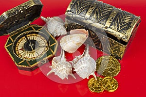 Compass and pirate coins on red background