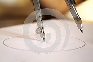 Compass resting on paper with pencil lead in midair