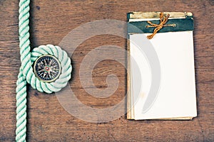 Compass, rope, old notebook on wooden table background