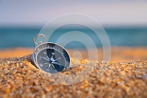 Compass on the sand close-up, sea in the background in sunset light. Finding navigation and paths. Sandy sea beach