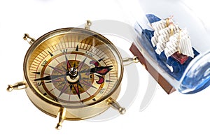 A compass and ship in a bottle on white