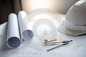 Compass tool, blueprints and helmet on working table