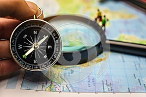 A compass that is used to travel with a magnifying glass and map that has a blurry background