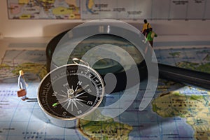 A compass that is used to travel with a magnifying glass and map that has a blurry background