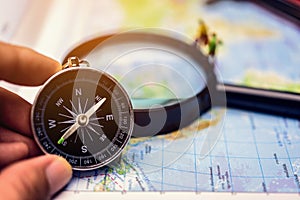 A compass that is used to travel with a magnifying glass and map that has a blurry background