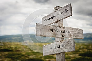 compassion wisdom faith text engraved on old wooden signpost outdoors in nature