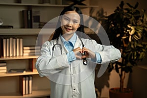 Compassionate Asian Female Doctor Gesturing Heart Sign in Clinic Office