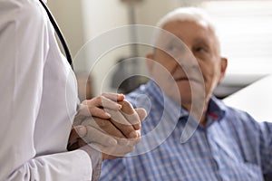 Compassionate female doctor nurse supporting consoling aged retired man patient