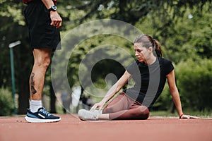 Compassionate man aiding his partner with a leg injury during a workout in a park