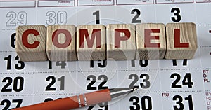 COMPEL - word on wooden cubes on the background of the calendar and pen