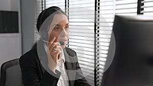 Competent female operator working on computer and while talking with clients.