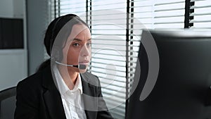 Competent female operator working on computer and while talking with clients.