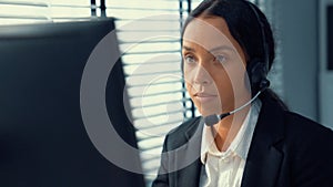 Competent female operator working on computer and while talking with clients.