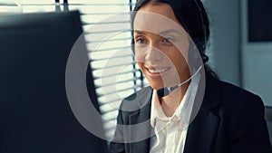 Competent female operator working on computer and while talking with clients.