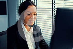 Competent female operator working on computer and while talking with clients.