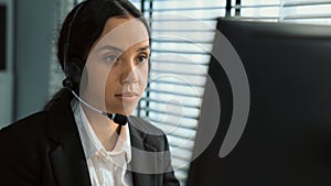 Competent female operator working on computer and while talking with clients.