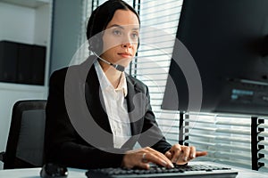 Competent female operator working on computer and while talking with clients.