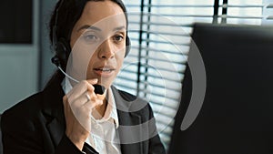 Competent female operator working on computer and while talking with clients.
