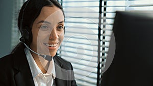 Competent female operator working on computer and while talking with clients.