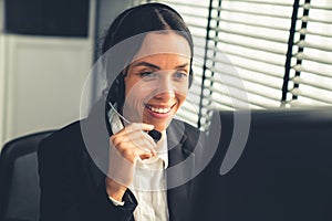 Competent female operator working on computer and while talking with clients.