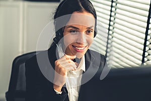 Competent female operator working on computer and while talking with clients.