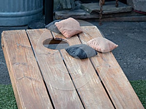 Competing black and beige beanbags sitting on cornhole platform