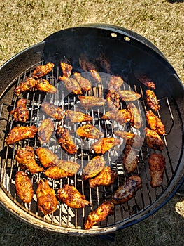 Competition Bbq chicken wing and dummies cooking on a Charcoal grill.