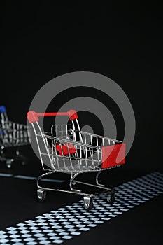 Competition concept. Red shopping cart crossing finish line