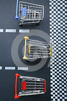 Competition concept. Shopping carts racing towards finish line, flat lay