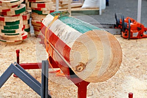 Competition lumberjacks, the marking log lies on a metal stand against the background of chainsaws and wooden slices in blur