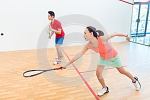 Competitive Chinese woman holding the racquet during a squash game