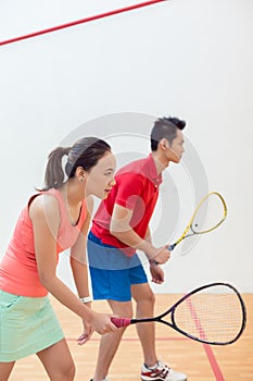 Competitive Chinese woman holding the racquet during a squash game