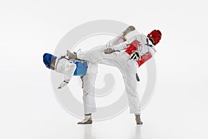 Competitive strong young men, taekwondo, karate athletes in motion, fighting, training isolated over white background