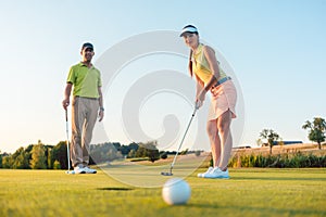 Competitive woman looking at the golf ball with disappointment