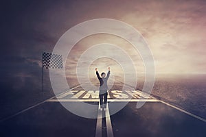 Competitive woman, raising hands up, celebrate on the road as crossing the finish line. Surreal challenge winning concept,