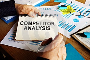 Competitor analysis report in the man hands photo