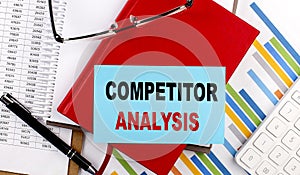 COMPETITOR ANALYSIS text on a sticky on red notebook on chart background