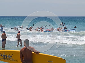 Competitors carrying surf racing boards into sea to start a race