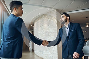 Competitors stand no chance against this partnership. two young businessmen shaking hands in a modern office.
