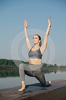 Complacent young woman doing yoga outdoors in a beautiful spot on a riverside