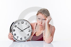 Complaining beautiful young woman holding a clock