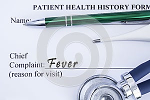 Complaint of Fever. Paper health history form, which is written on the patients chief complaint of Fever, surrounded by a stethosc