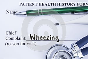 Complaint of wheezing. Paper health history form, which is written on the patient`s chief complaint of wheezing, surrounded by a s