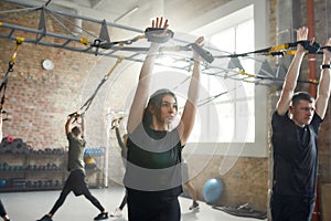 Complete Body. Athletic young woman doing fitness training exercises at industrial gym. Push-up, group workout concept