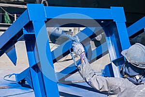 After complete fabrication at an industrial factory, the painter uses a spray gun to paint a steel structure