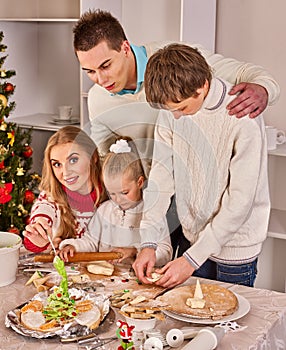 Complete family with children rolling dough in Xmas kitchen.